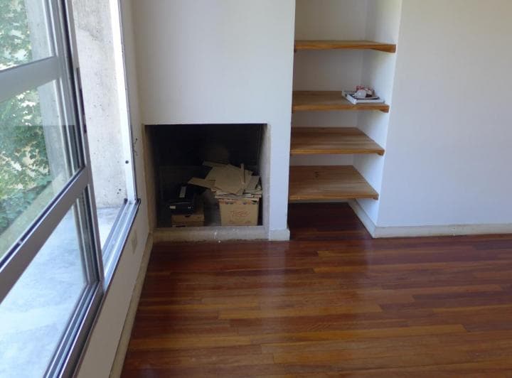 Detalle del living con hogar a leña y estantes de madera.