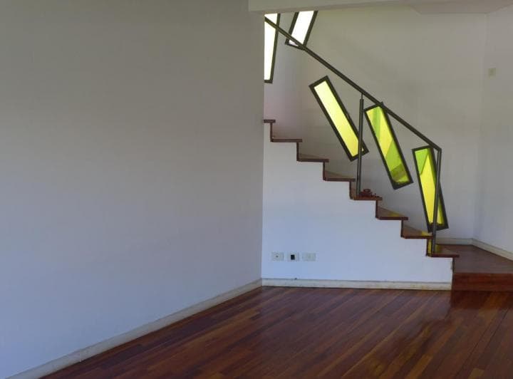 Pasillo con escalera de madera y baranda artística de vidrios de colores.