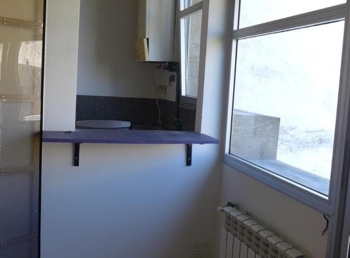 Cocina con barra, radiador, y ventana con vista exterior.