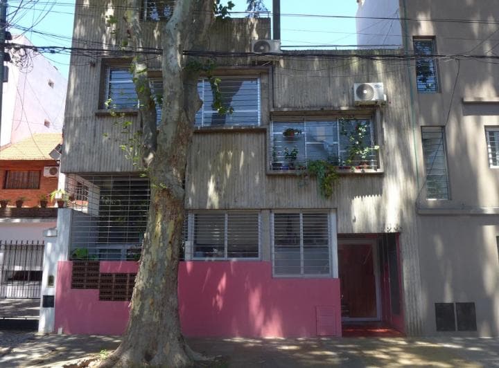 Fachada de un edificio de hormigón con detalles en color rosa.