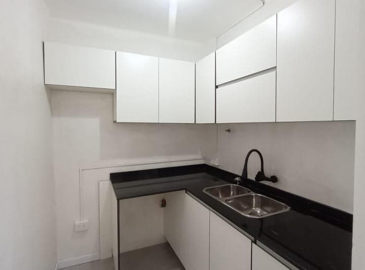 Cocina con mesada negra, bacha doble y muebles blancos.