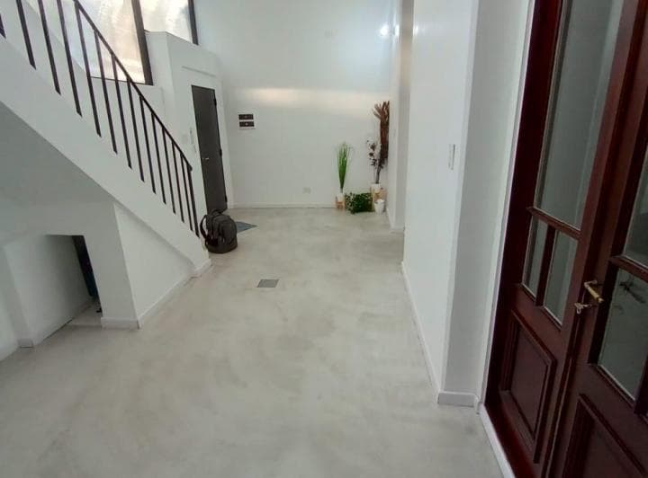 Living amplio y vacío con escaleras, decoración y puertas de madera.