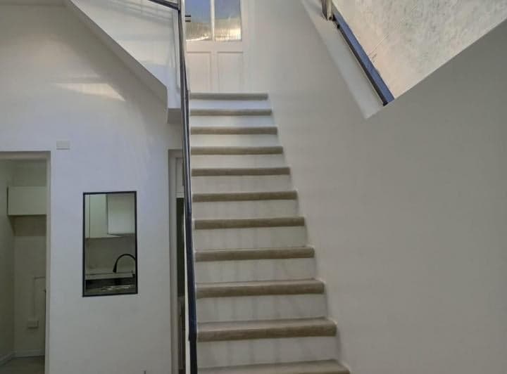 Pasillo con escaleras que suben y vista a la cocina.