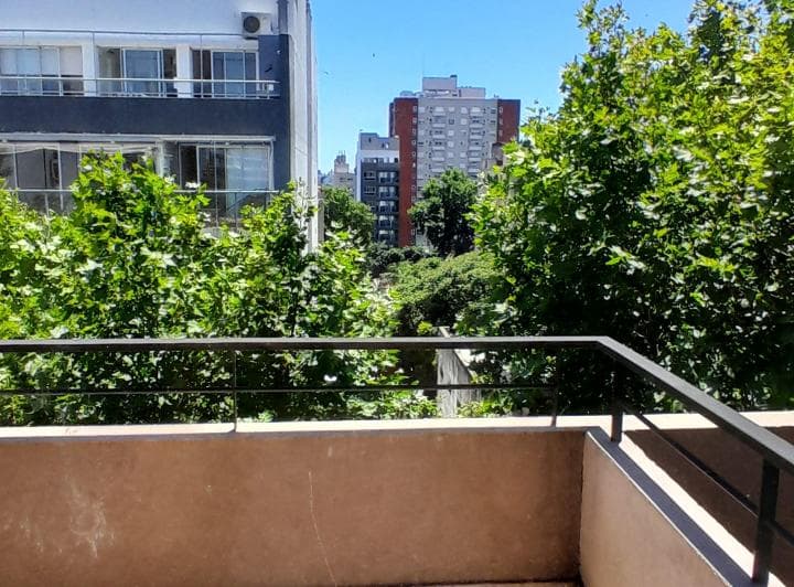Balcón con baranda y vista a árboles y edificios.