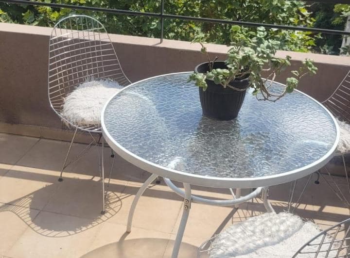 Balcón con mesa de vidrio y sillas.