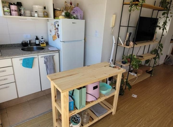 Cocina con mesada, heladera blanca y mueble auxiliar de madera.