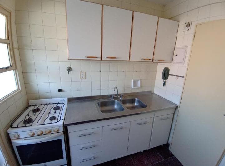 Cocina con mesada, bacha doble, anafe y alacenas blancas.