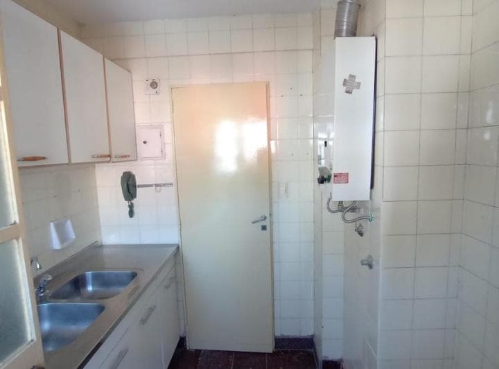 Cocina con termotanque, bacha y azulejos claros en la pared.