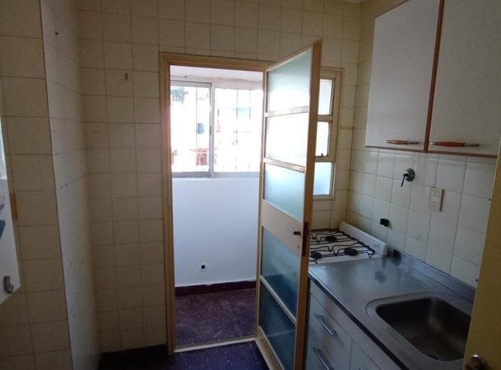 Cocina con vista al lavadero a través de una puerta abierta.