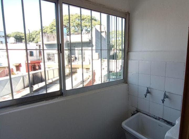 Lavadero con pileta de lavar, canillas y ventana con rejas.