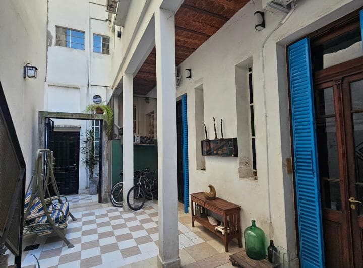 Patio exterior con columnas, piso damero, bicis y persianas azules.