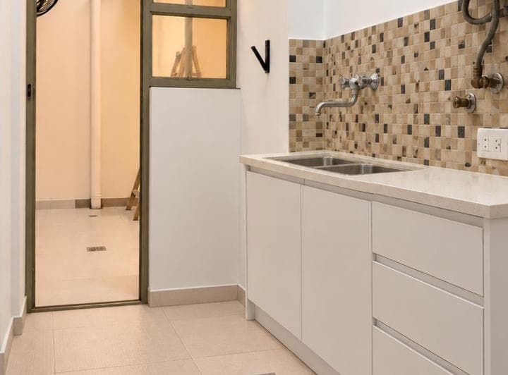 Cocina con mesada blanca, bacha doble y revestimiento con venecitas.