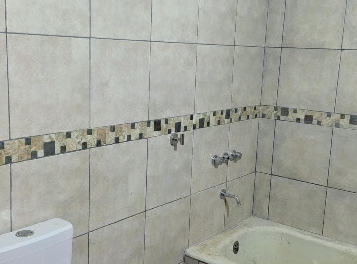 Baño con bañera, inodoro, grifería de ducha y azulejos claros.
