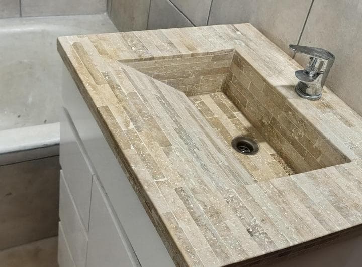Baño con vanitory de piedra, bacha y grifo modernos.