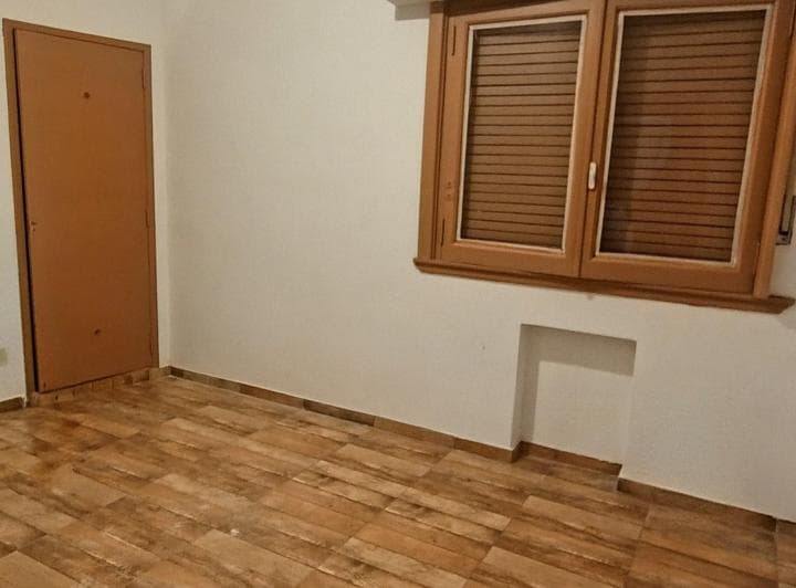 Dormitorio vacío con ventana de madera con persiana y puerta.