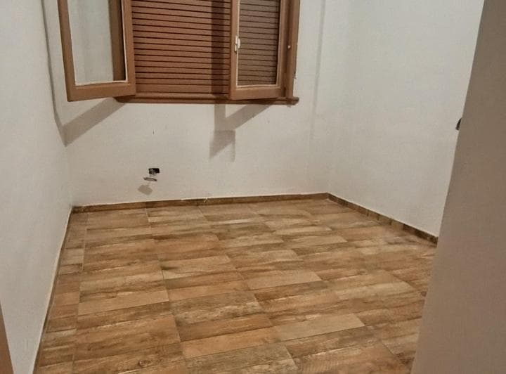Dormitorio vacío con ventana de madera y piso símil madera.