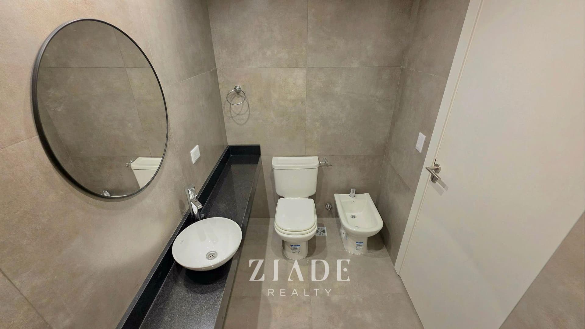 Baño con inodoro, bidet y vanitory con bacha de loza redonda y grifería de diseño.
