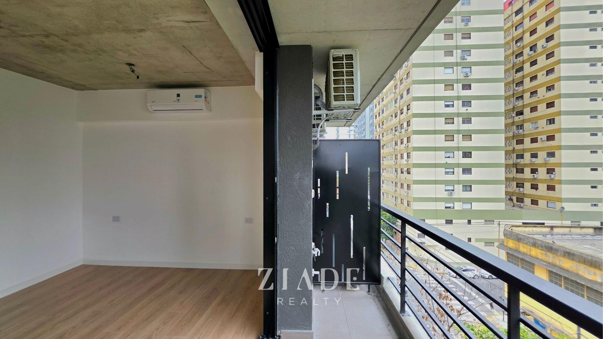 Balcón exterior con baranda de metal negro y vista a edificios de la ciudad.