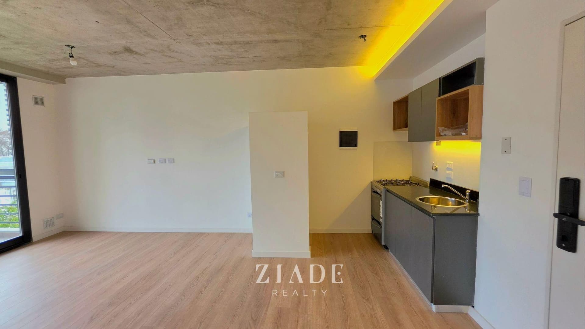 Cocina integrada con anafe, bacha, alacenas y ventana al exterior.