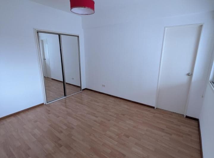Dormitorio con placard de puertas espejadas y piso de madera.