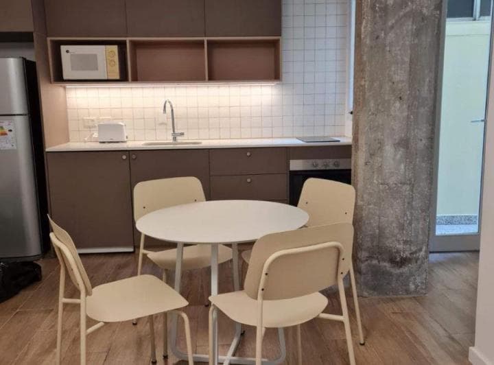 Cocina integrada con mesada, bacha, anafe, horno, heladera y alacenas, junto a una mesa.