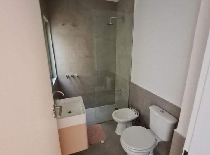Baño con ducha y mampara de vidrio, inodoro, bidet y lavatorio moderno.