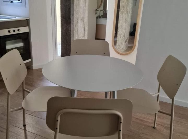 Comedor con mesa redonda y sillas, al fondo se ve parte de la cocina.
