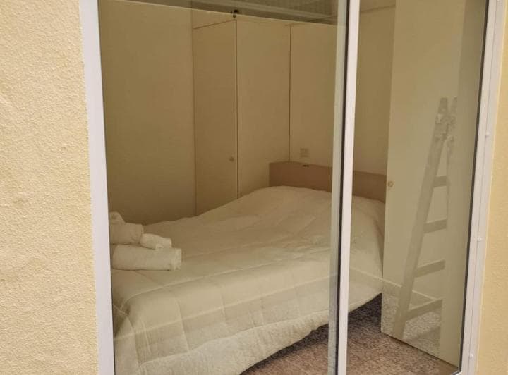 Dormitorio con cama y armario empotrado, visto a través de un ventanal.