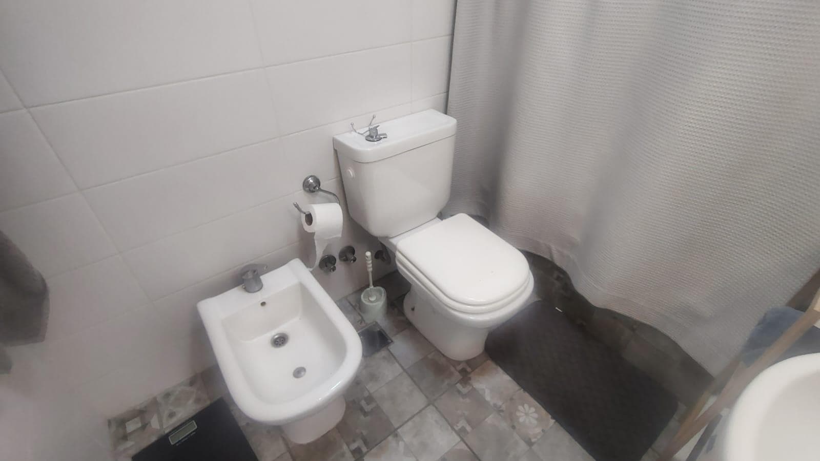 Baño completo con inodoro, bidet y cortina de ducha.