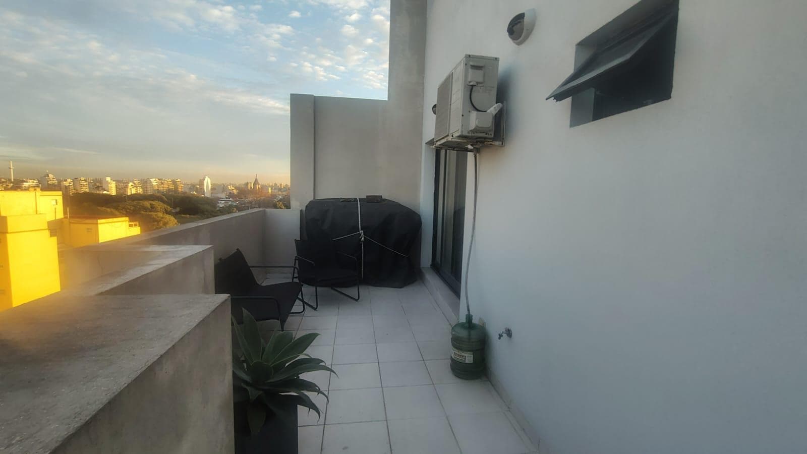Terraza exterior con aire acondicionado y vista a edificios.