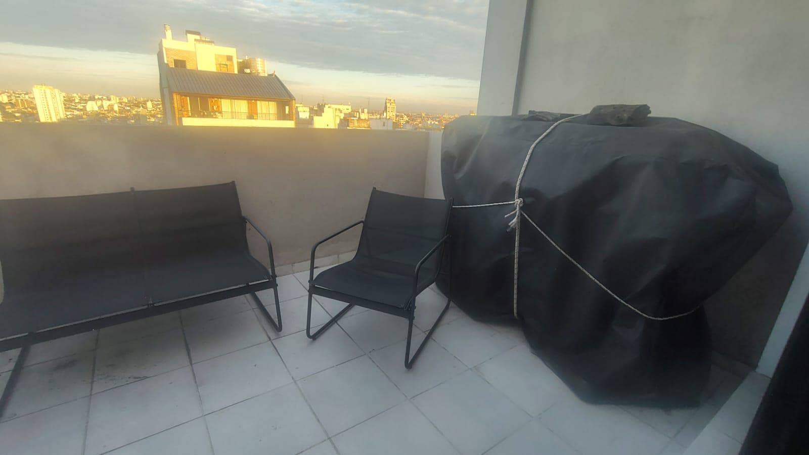 Terraza con mobiliario exterior y parrilla cubierta.