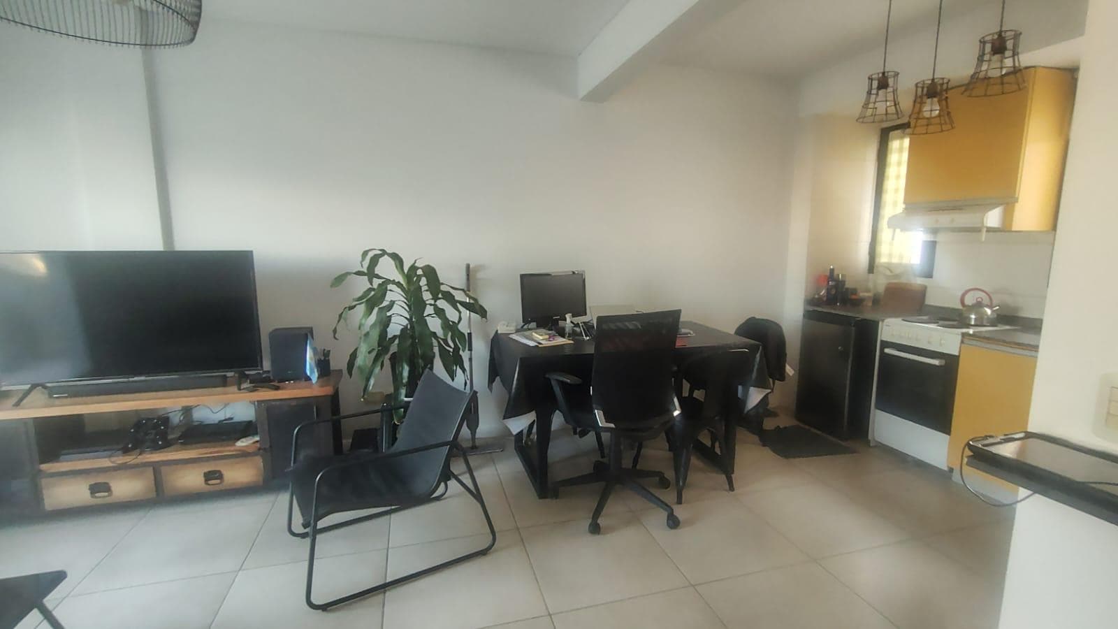 Living-comedor con TV, mesa de comedor y sector de cocina integrado.