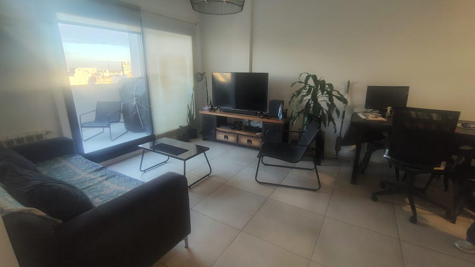 Living con sillón, televisor y mesa de comedor.