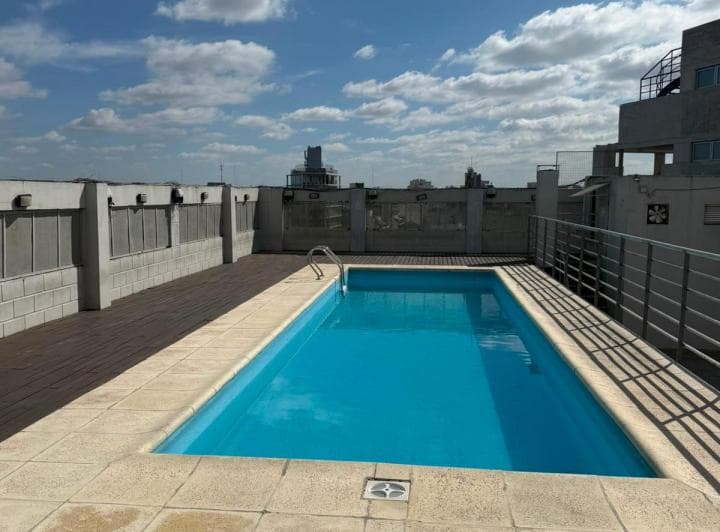 Pileta rectangular en la azotea de un edificio con vistas a la ciudad.