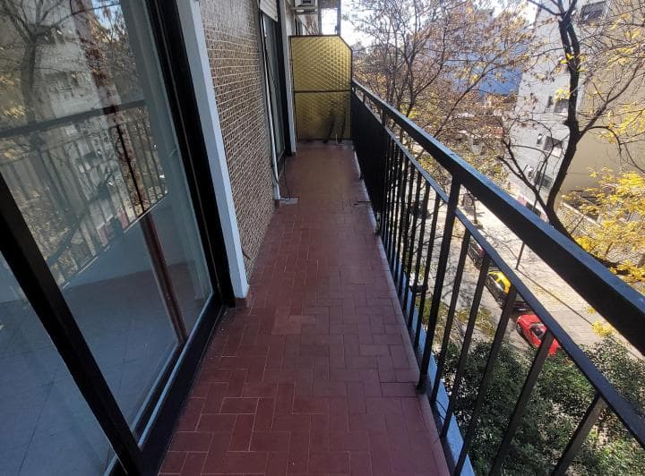 Balcón con rejas y piso de baldosas, vista parcial a la calle.