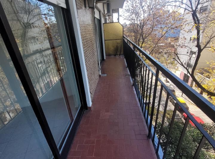 Balcón de baldosas rojas con baranda de hierro negro, vista externa.