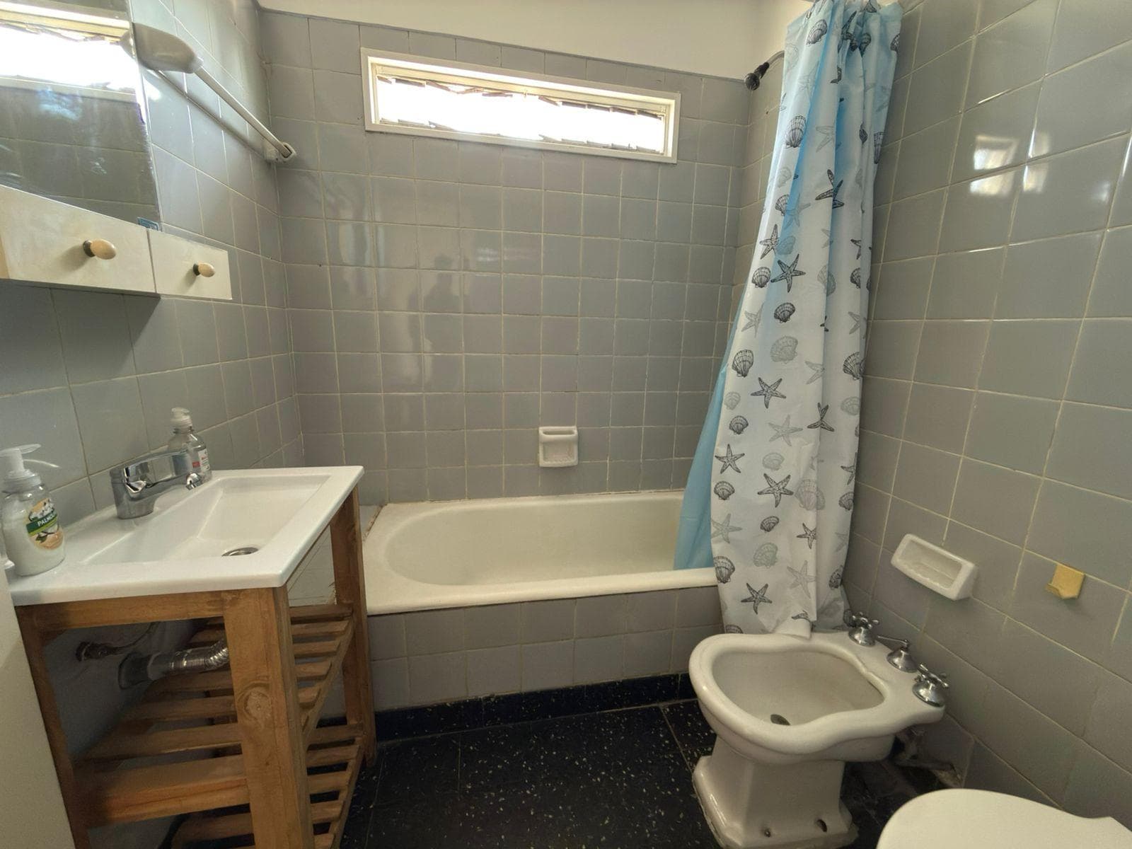 Baño completo con bañera, bidet y lavatorio de madera.