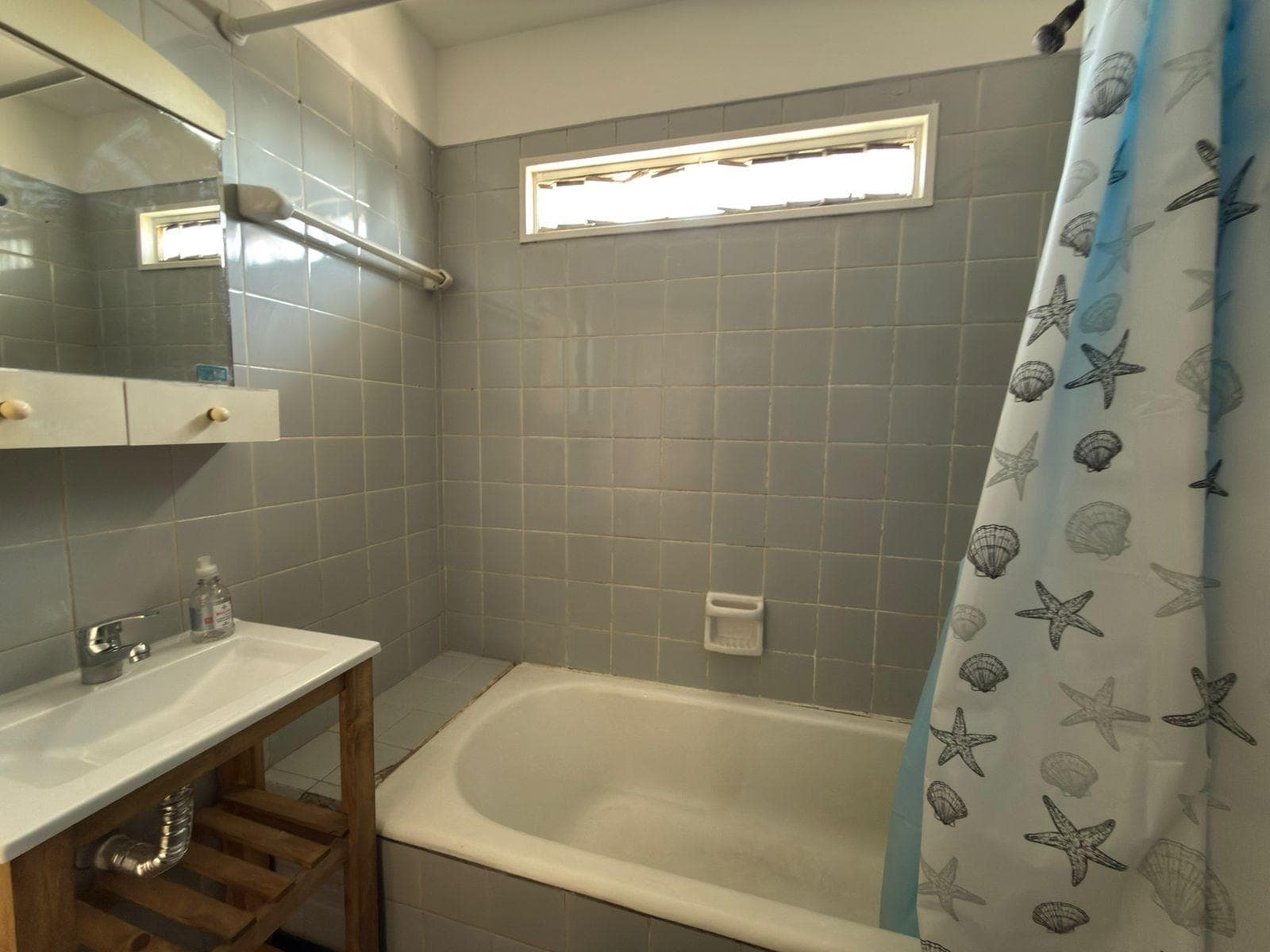 Baño con bañera, lavatorio y cortina de ducha.