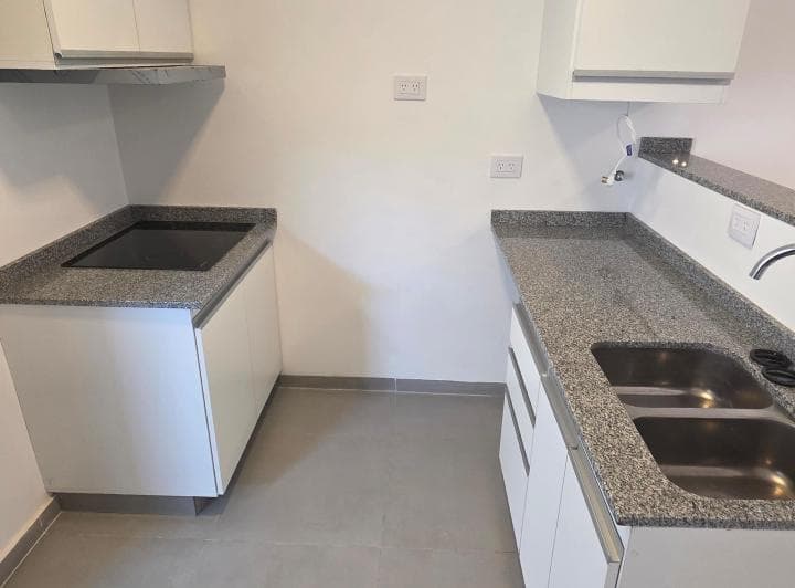 Cocina con mesada de granito, bacha doble y anafe eléctrico empotrado, alacenas.