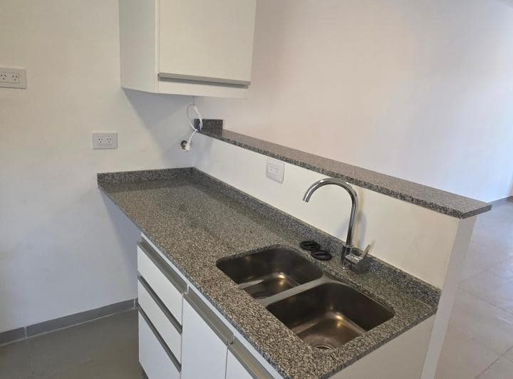Detalle de cocina con mesada de granito, bacha doble y grifería monocomando.