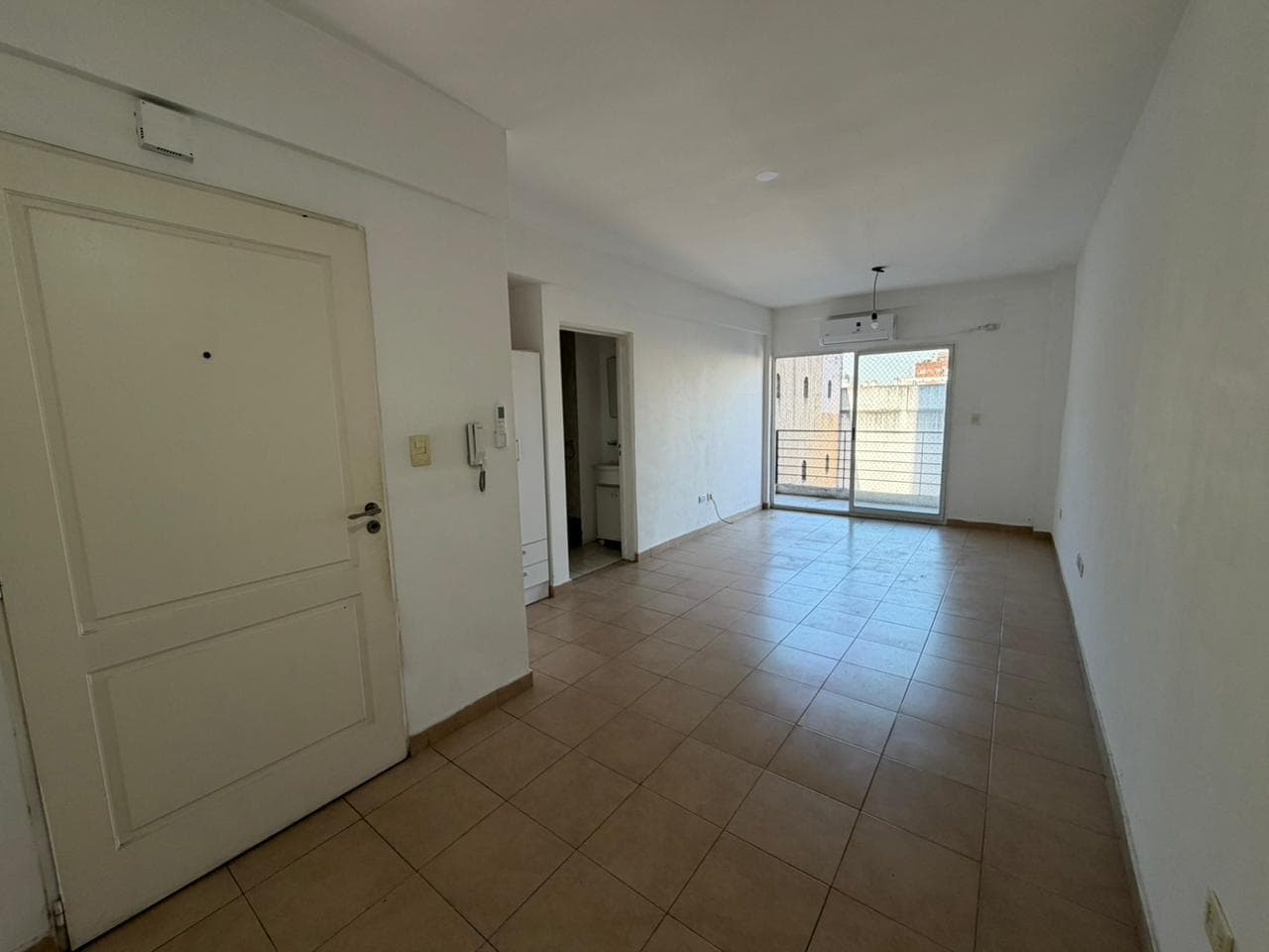 Living con puerta de entrada, aire acondicionado y salida al balcón.