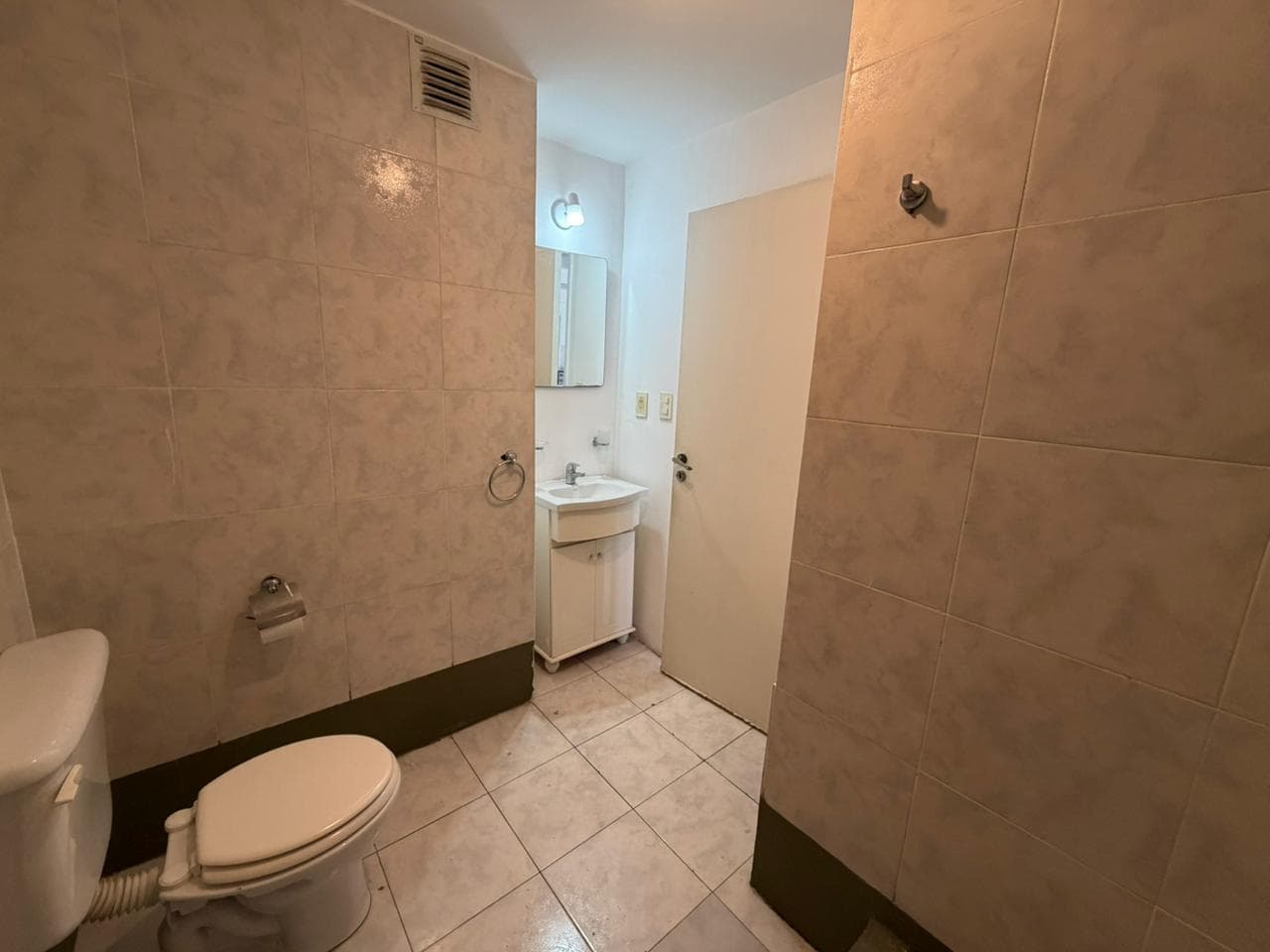 Baño con inodoro, vanitory y espejo.