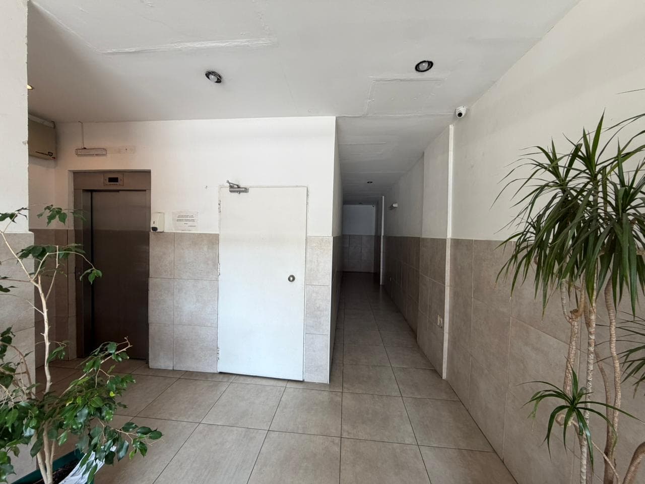 Pasillo de edificio con ascensor y puertas de departamentos.