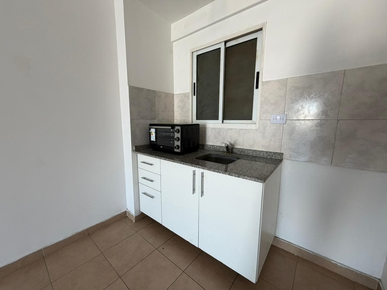 Cocina compacta con mesada, bacha y horno microondas.