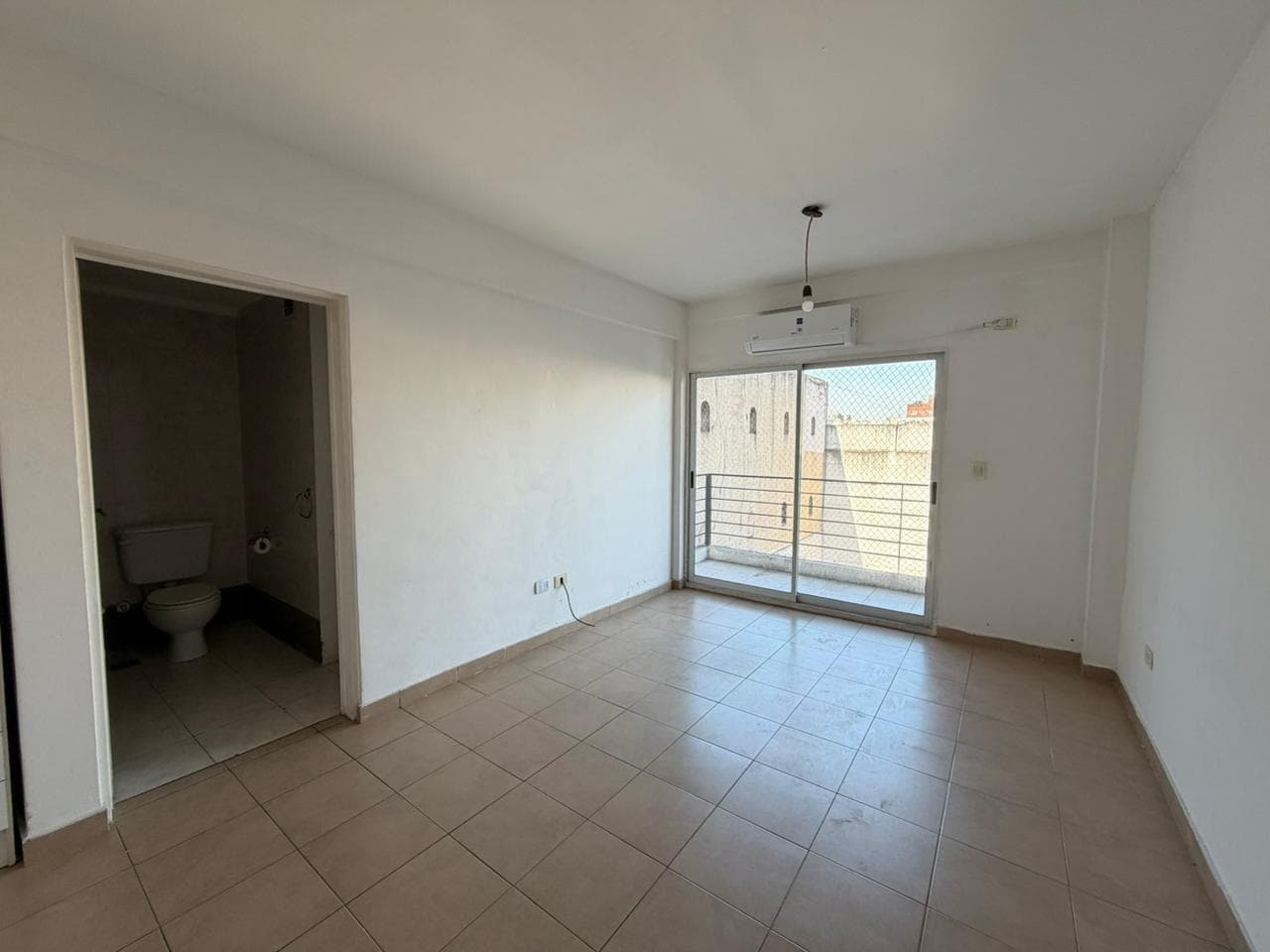 Living con salida al balcón y puerta de acceso al baño.