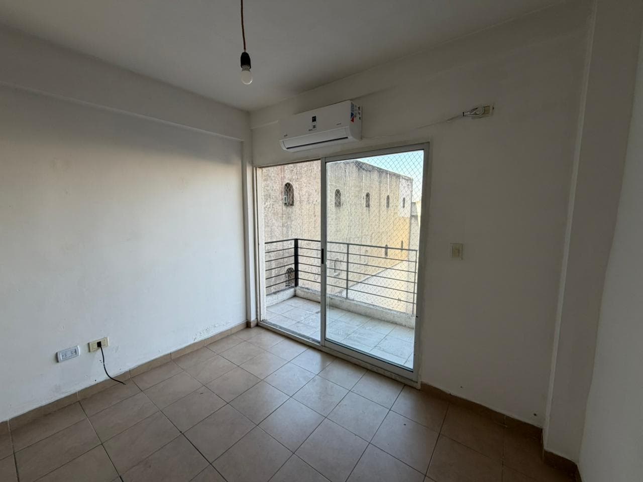 Living con aire acondicionado y puerta corrediza al balcón.