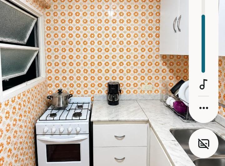 Cocina con anafe, bacha, ventana y alacenas blancas, con azulejos estampados.