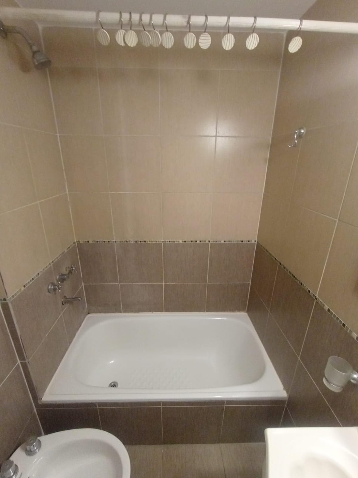 Bañera con ducha de pared y azulejos en el baño.
