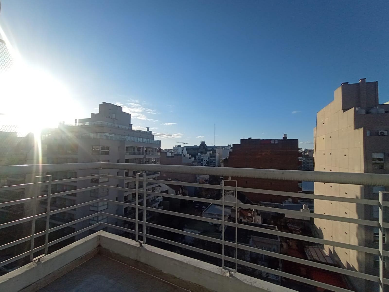 Balcón terraza con barandas metálicas y vista a la ciudad.