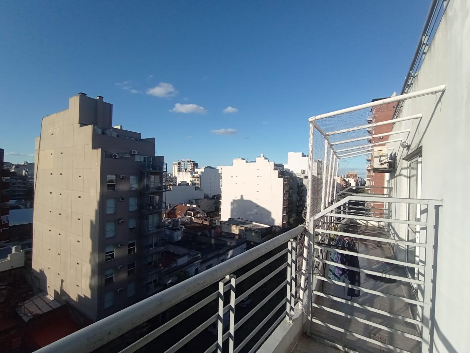 Balcón terraza con barandas metálicas y vista urbana.
